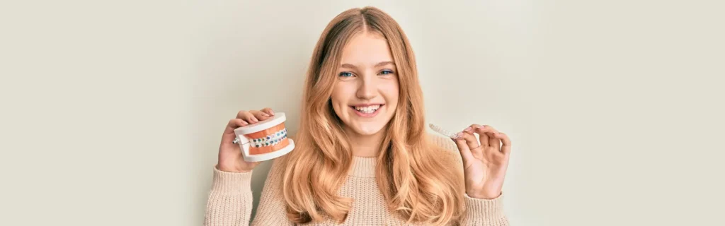 happy client holding an artificial mouth piece to show her good teeth in sd clinic